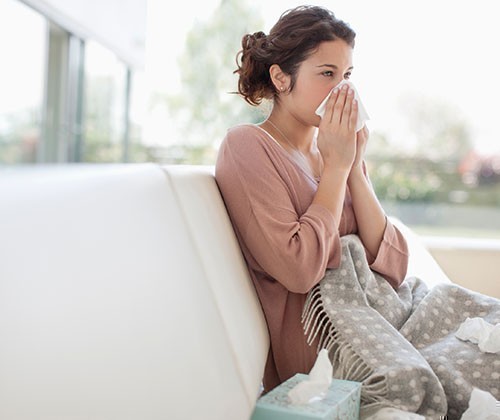 Woman blowing nose with tissue